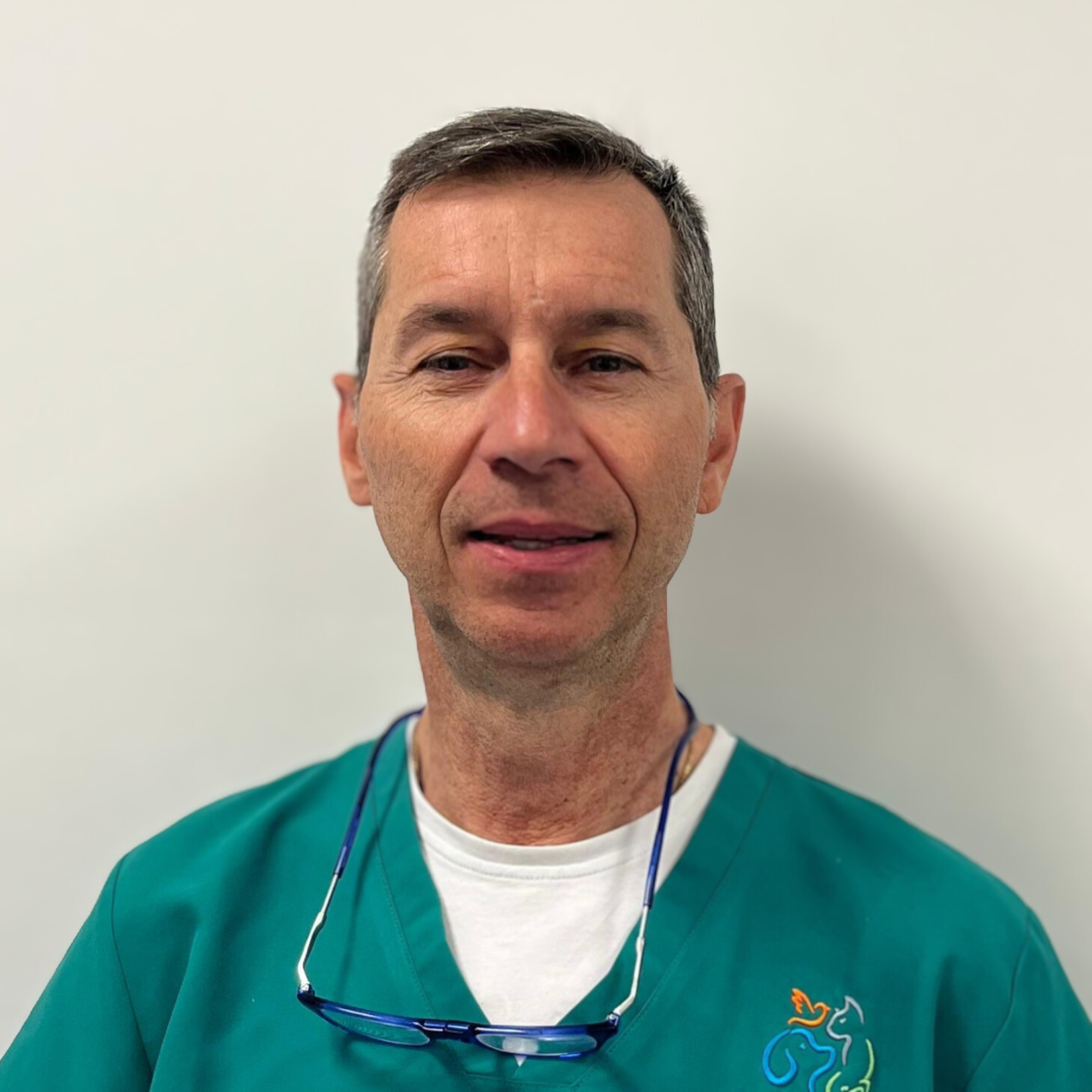 Un uomo, che ricorda Daniele De Zen, è in piedi su uno sfondo bianco semplice, con una camicetta verde sopra una camicia bianca. Un paio di occhiali pendono dal colletto. Con i capelli corti e grigi, guarda la telecamera con un'espressione neutra.